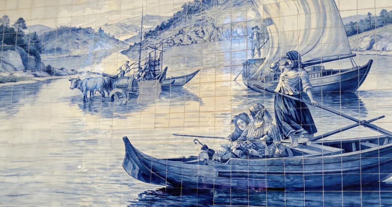 Um mural de azulejos azuis e brancos que mostra pessoas em barcos de madeira em um rio com montanhas ao fundo.