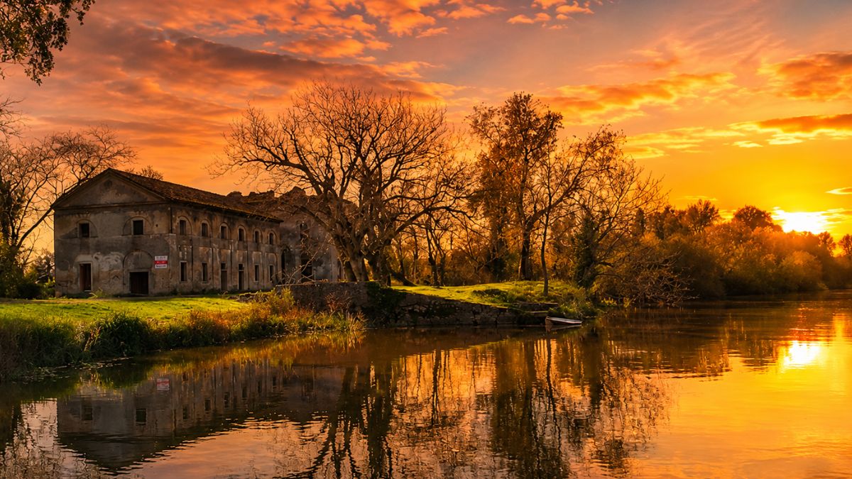 Fachada em ruínas do histórico Palácio das Obras Novas em Azambuja, Portugal, refletida no Rio Tejo durante um pôr do sol alaranjado.