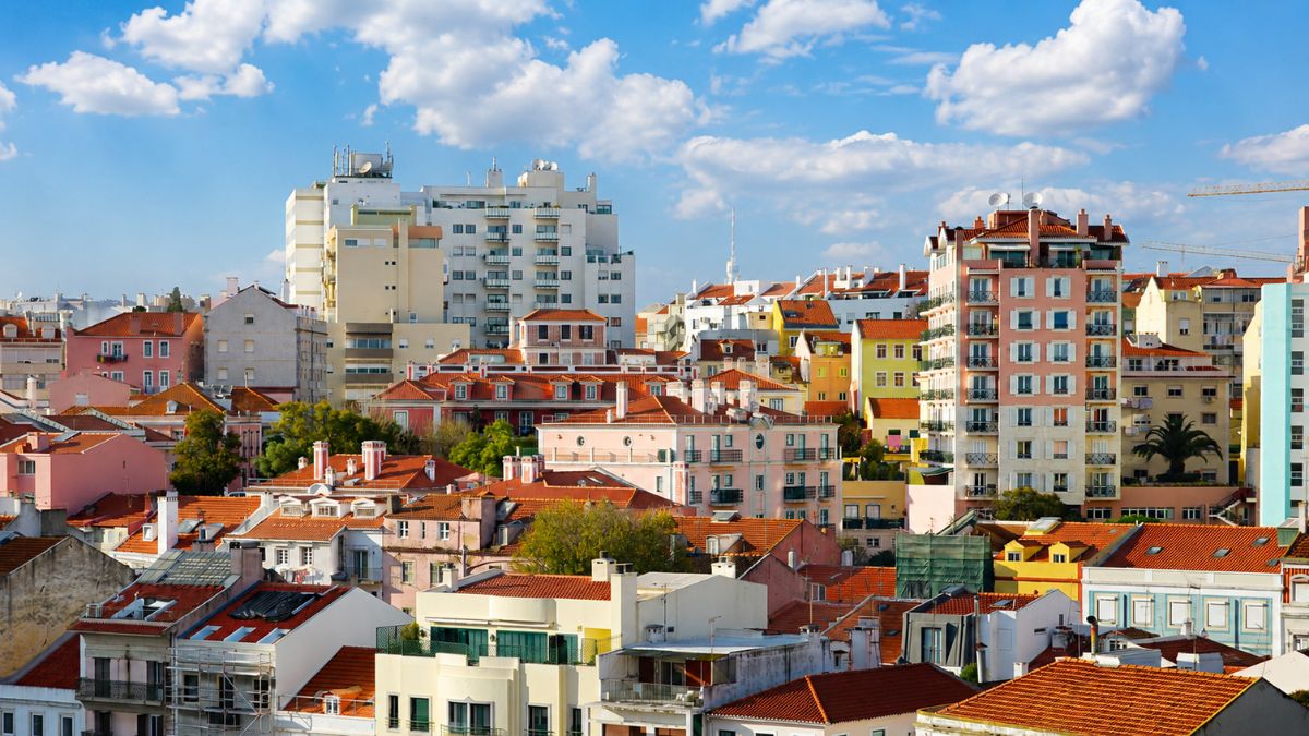 Vista panorâmica de prédios residenciais e habitações com telhados tradicionais sob céu azul na cidade de Lisboa em Portugal.