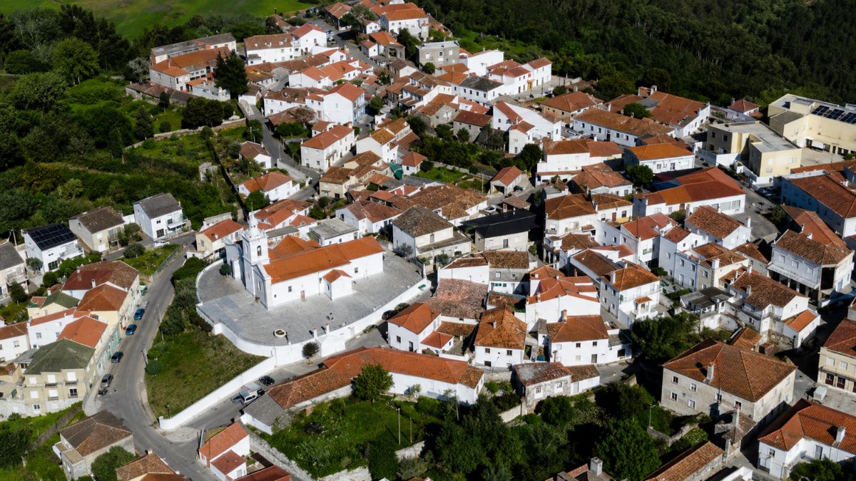 Vista aérea da vila do Cadaval em Portugal com suas casas brancas de telhados vermelhos destacando a igreja matriz centralizada e cercada pela vegetação da região.