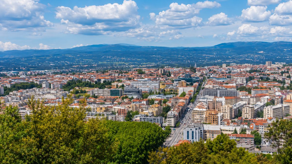 Uma imagem panorâmica de Braga sob um céu azul, revelando a extensão urbana da cidade e as colinas distantes.