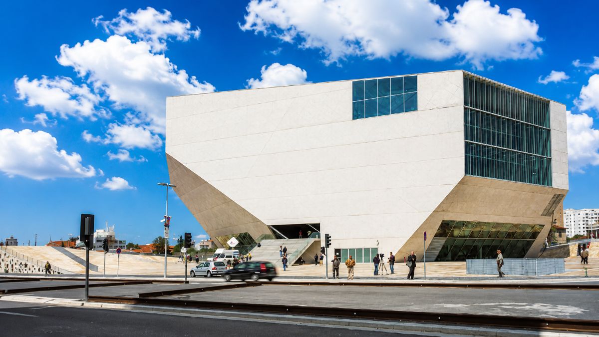 Edifício de arquitetura contemporânea e poligonal da Casa da Música com grandes panos de vidro sob céu azul no Porto