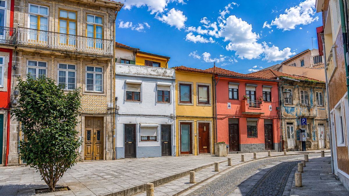 Fachada de casas tradicionais coloridas com arquitetura típica portuguesa em uma rua de paralelepípedos no centro histórico de Vila do Conde.