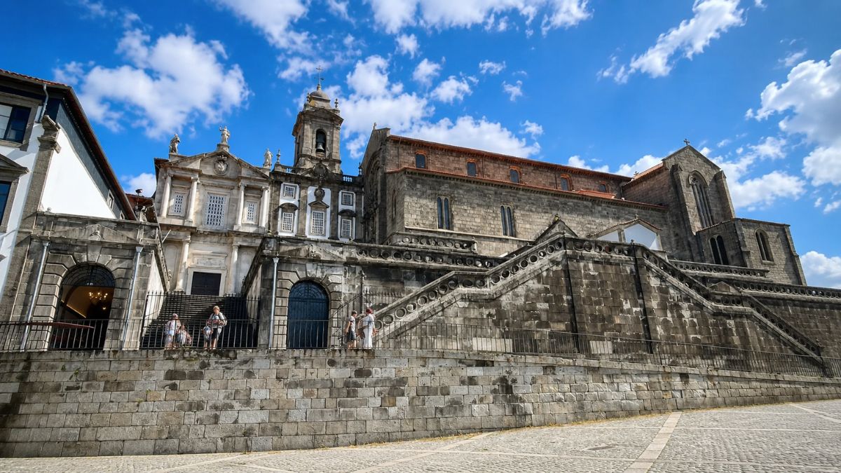 Vista frontal da Igreja de São Francisco no Porto com sua arquitetura gótica e barroca sob um céu azul com nuvens.