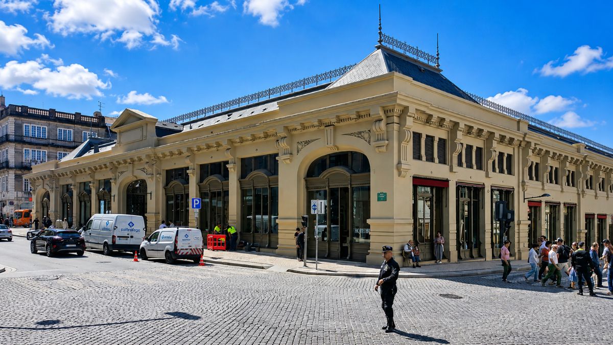 Fachada externa do Mercado do Bolhão em tom amarelo claro com grandes janelas em arco, vans de serviço e pedestres na calçada sob céu azul.