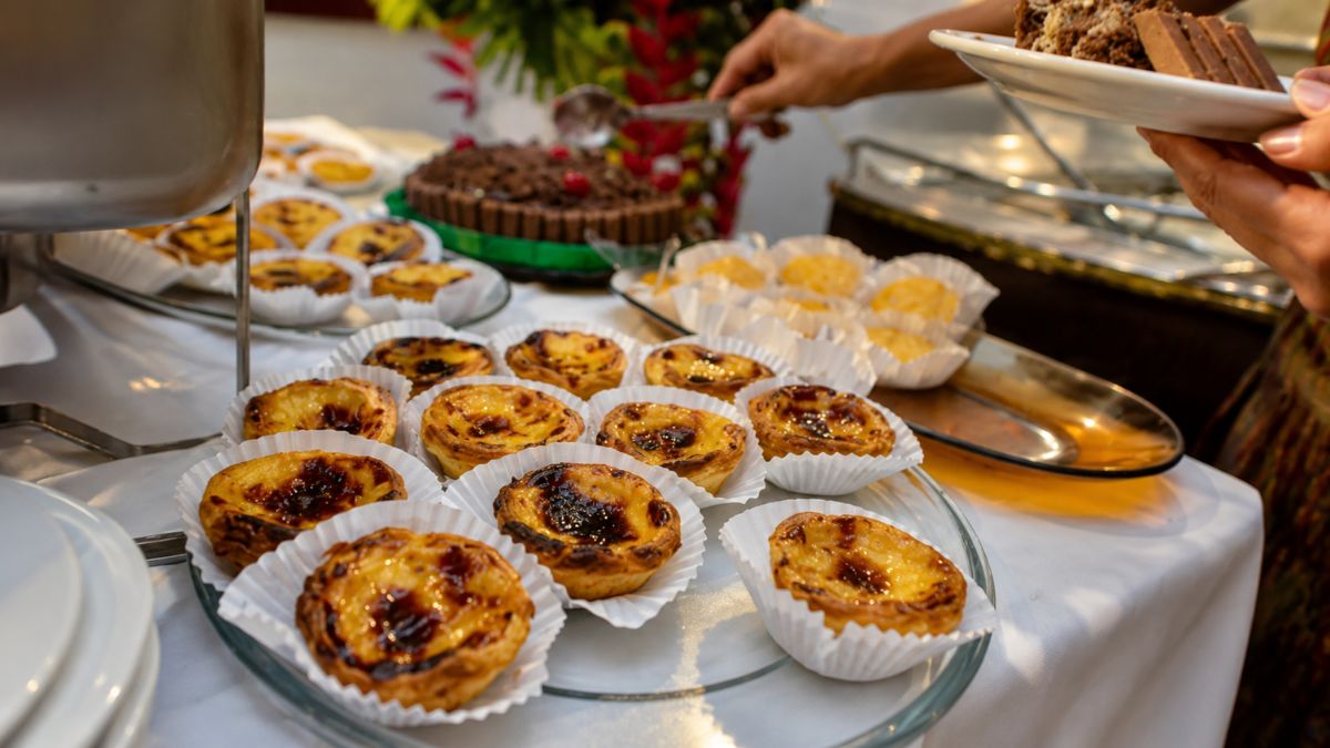 Mesa de doces finos com destaque para pastéis de nata tradicionais portugueses servidos em evento social requintado no Porto