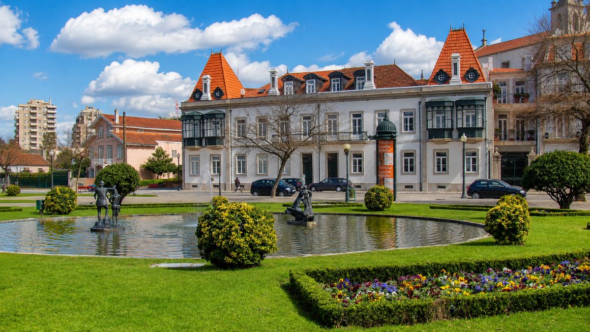 Chafariz ornamental e canteiros de flores no Jardim do Passeio Alegre em frente a palacetes históricos na Foz do Douro Porto