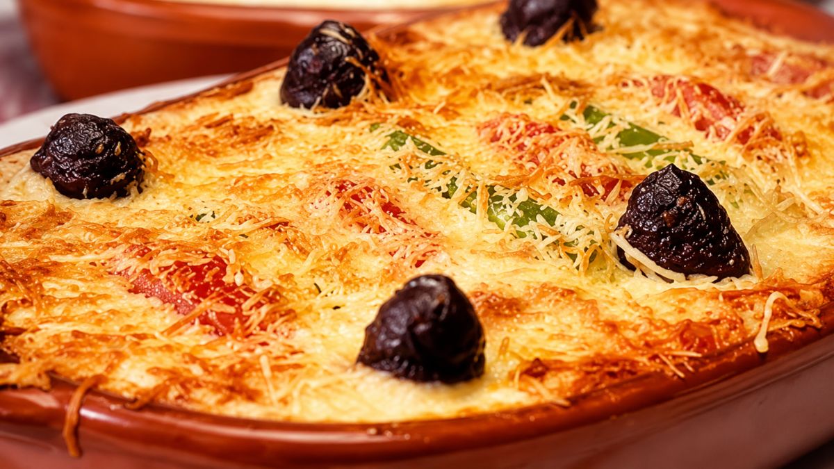Fotografia em close de uma travessa de barro contendo Bacalhau à Zé do Pipo. A superfície está coberta por purê de batatas com uma crosta dourada e gratinada de queijo ralado. Quatro azeitonas pretas grandes estão dispostas sobre o gratinado, e tiras de pimentão vermelho e verde são visíveis sob a cobertura.
