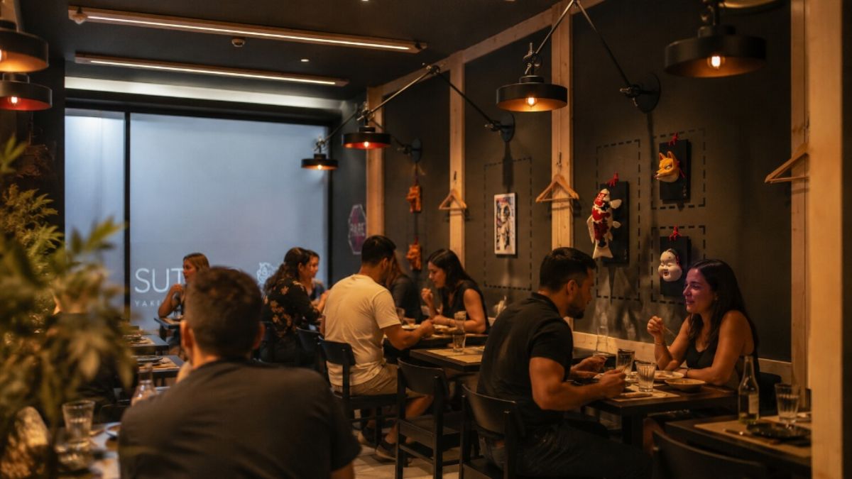 Pessoas jantando em mesas organizadas dentro de um restaurante moderno com iluminação acolhedora em Coimbra, Portugal.