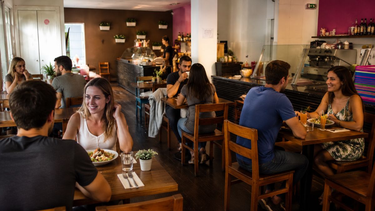 Clientes almoçando em mesas de madeira no salão iluminado do restaurante Pimenta Rosa em Porto Portugal.