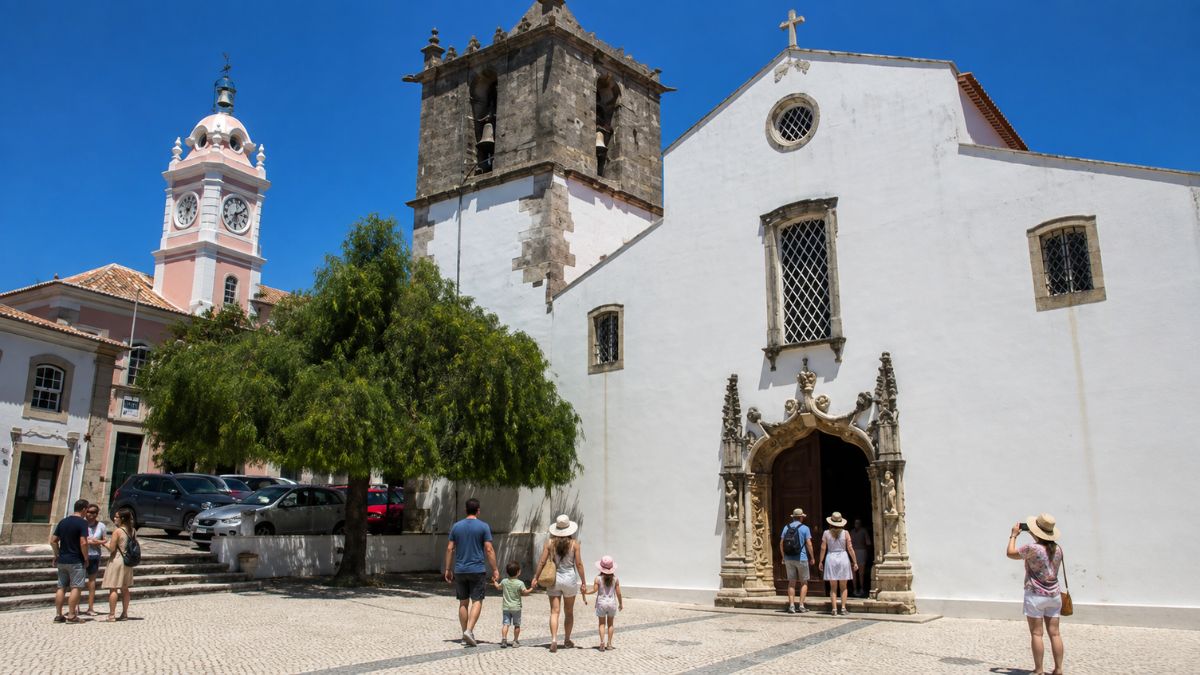 Pessoas e famílias visitando a Igreja Matriz de Nossa Senhora da Salvação em uma praça histórica de Arruda dos Vinhos.