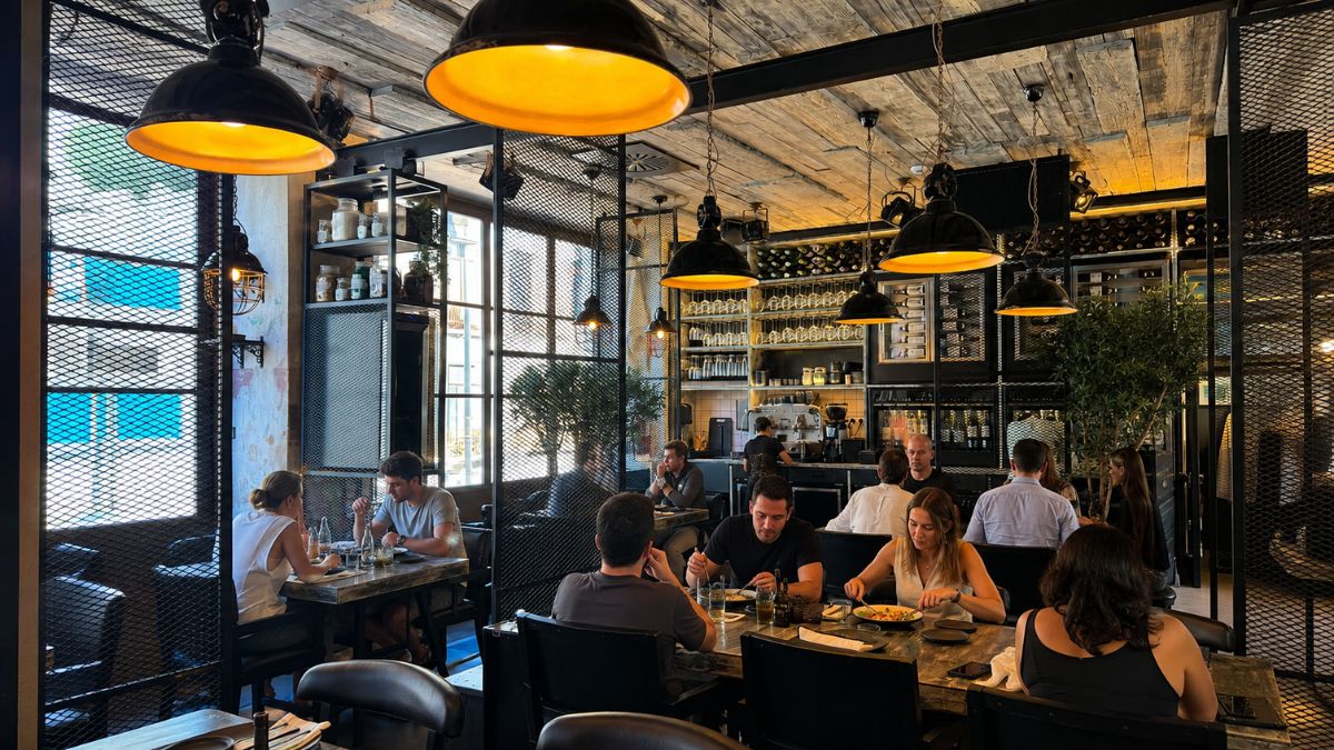 Pessoas almoçando no salão do restaurante Culto ao Bacalhau com iluminação industrial no Porto Portugal.