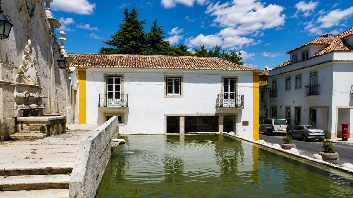 Vista do Chafariz Pombalino com espelho d'água e arquitetura tradicional no centro histórico do município de Arruda dos Vinhos, Portugal.