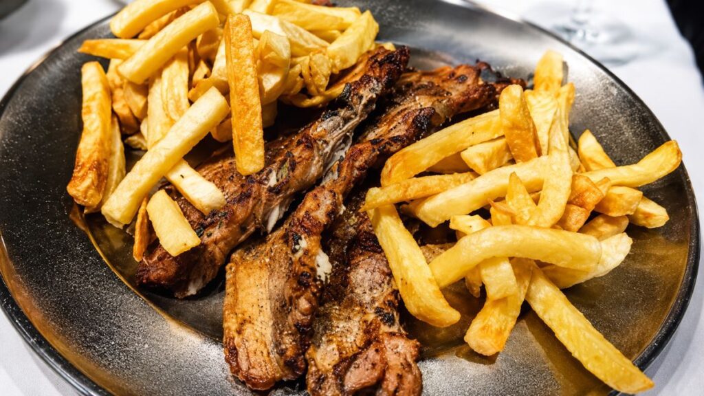 Prato de inox com entrecosto de porco grelhado na brasa e acompanhado de batatas fritas no Restaurante O Fuso em Arruda dos Vinhos.