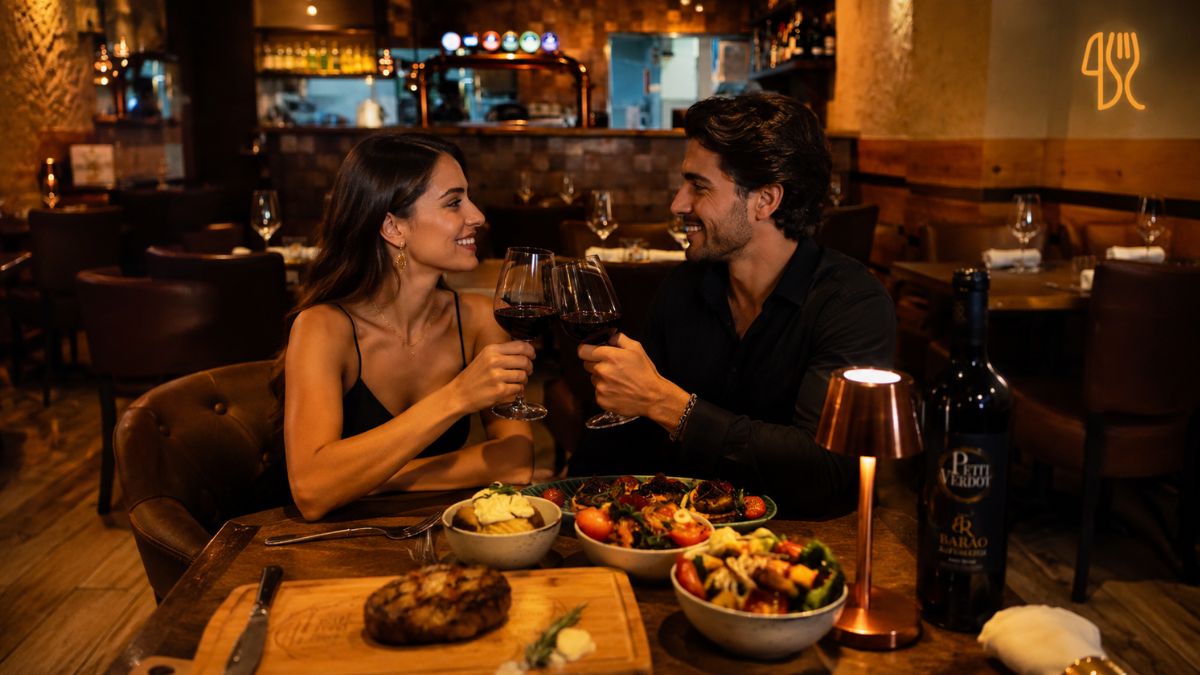 Casal desfruta de jantar romântico com cortes nobres de carne e vinho no ambiente acolhedor do Faaron Steakhouse em Faro.