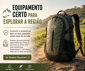 Uma mochila de caminhada verde e preta apoiada sobre uma pedra com vista para vinhedos e uma fortaleza na colina em Arruda dos Vinhos.
