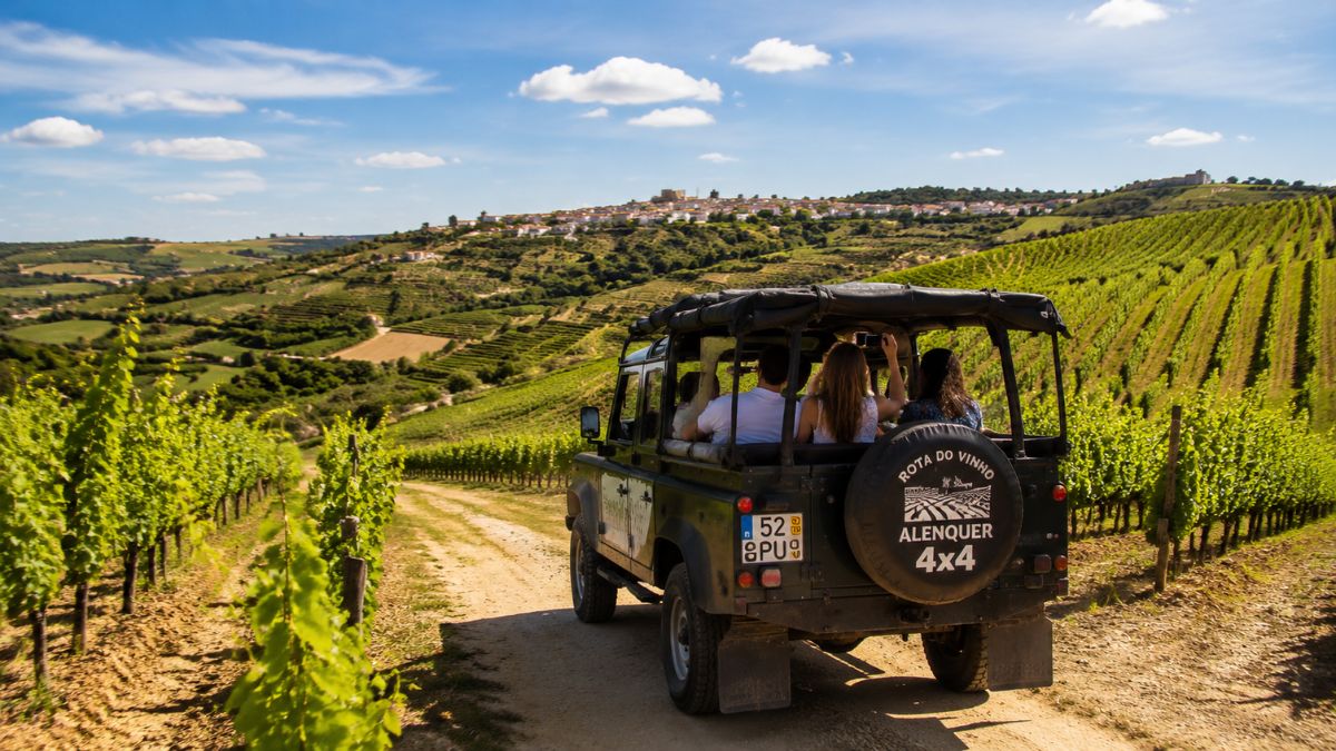 Veículo todo o terreno preto com passageiros num caminho de terra a percorrer as vinhas da Rota do Vinho em Alenquer.
