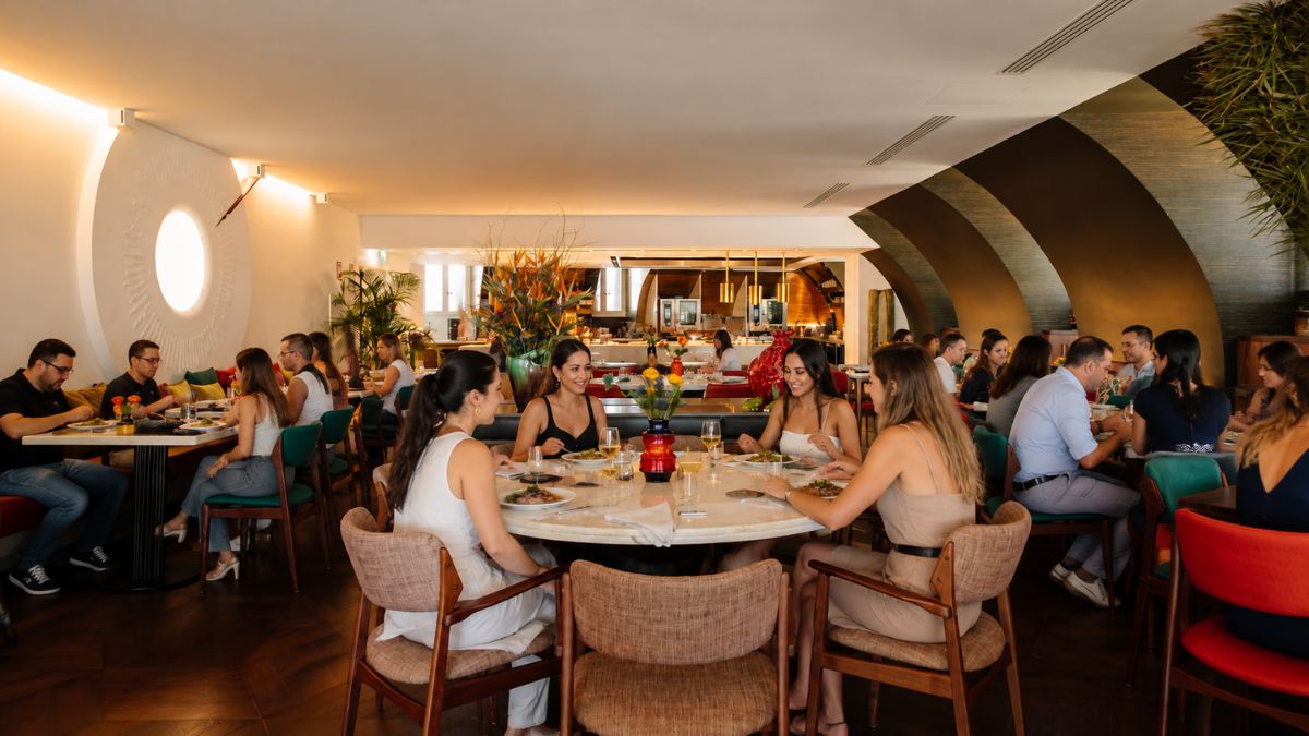 Pessoas reunidas em mesa redonda jantando no elegante salão do restaurante BAHR no Bairro Alto Hotel em Lisboa.