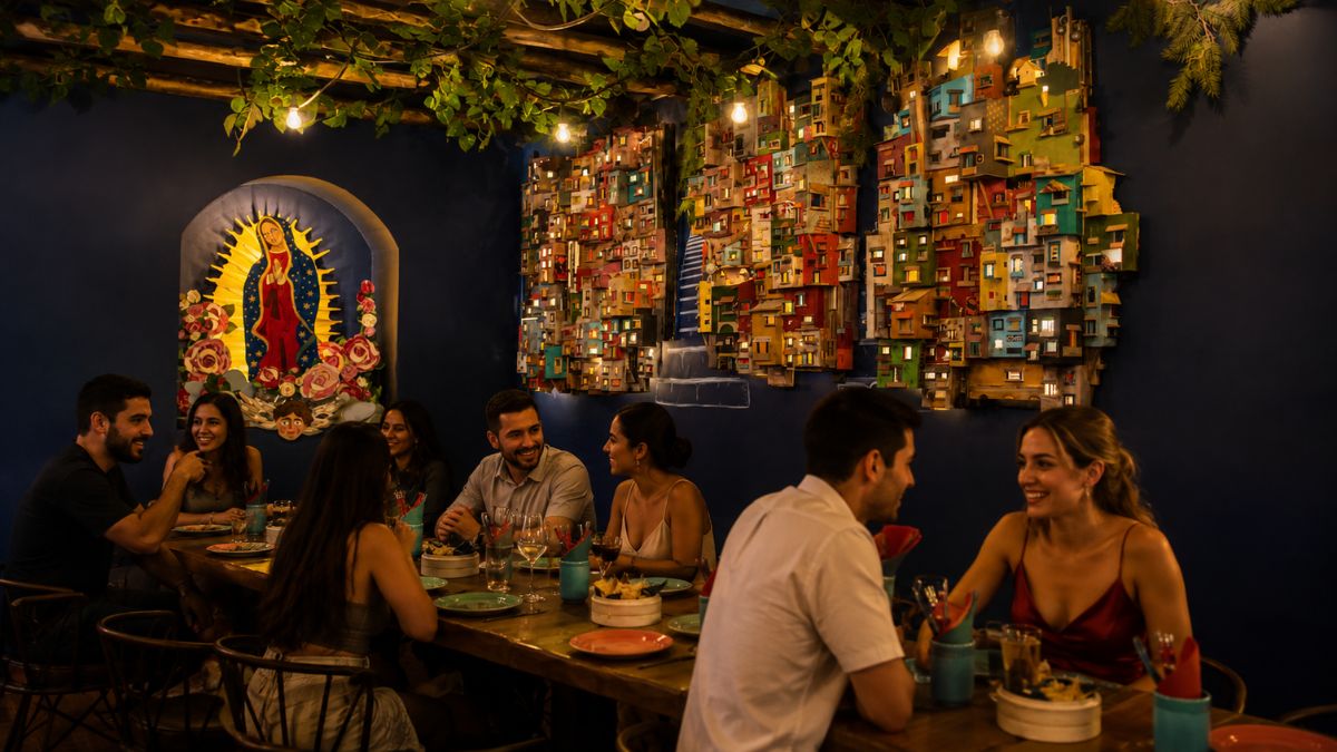 Pessoas reunidas em mesas de madeira no restaurante El Santo em Lisboa com decoração temática mexicana, iluminação acolhedora e arte na parede.