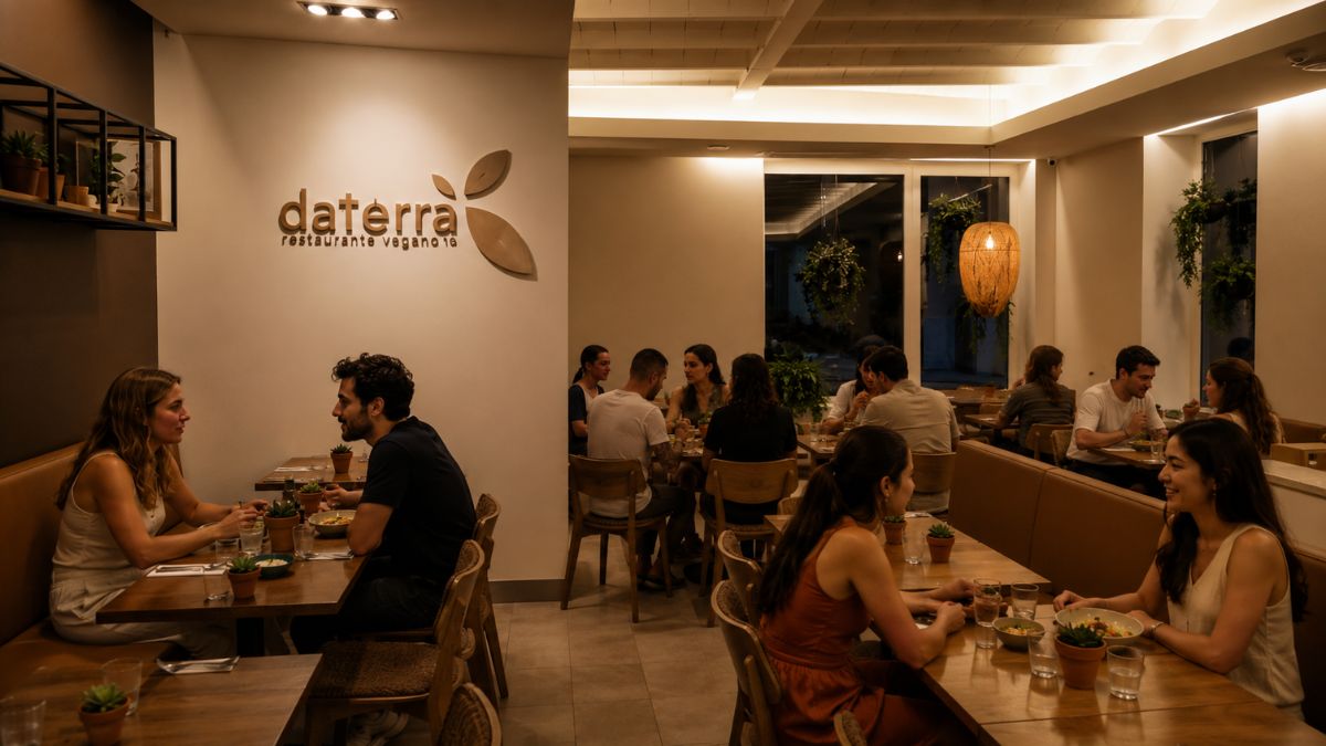Clientes jantando no salão moderno do restaurante vegano daTerra no Bairro Alto em Lisboa com iluminação acolhedora e logotipo na parede.